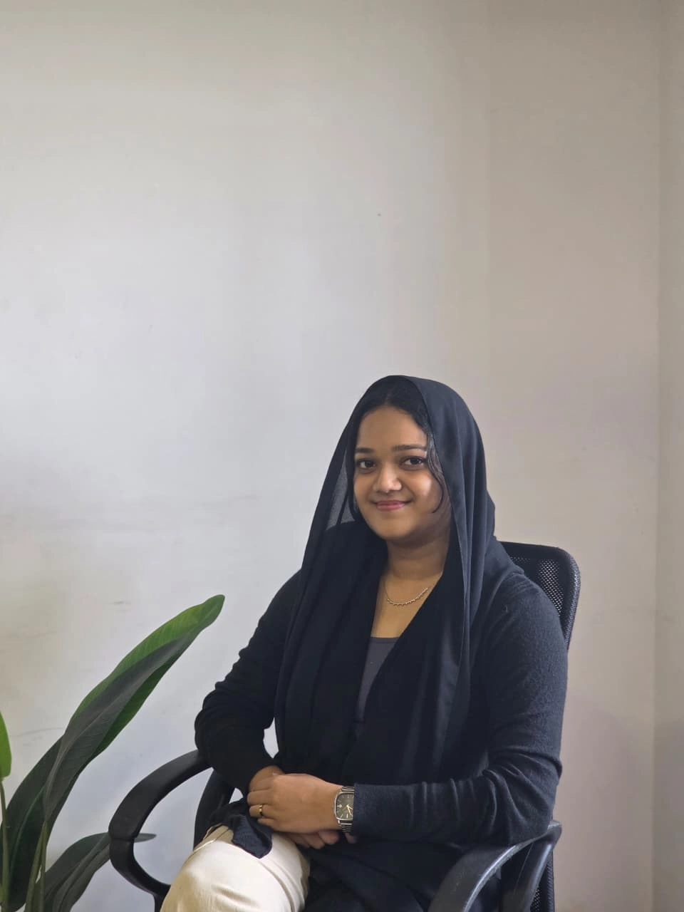 Freelance digital marketing specialist in Thrissur , sitting confidently in an office chair wearing a black hijab and professional attire.